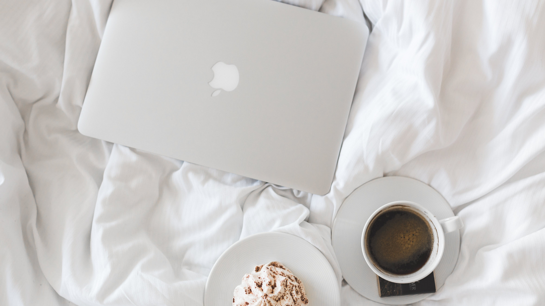 Apple MacBook on comfy bed with coffee